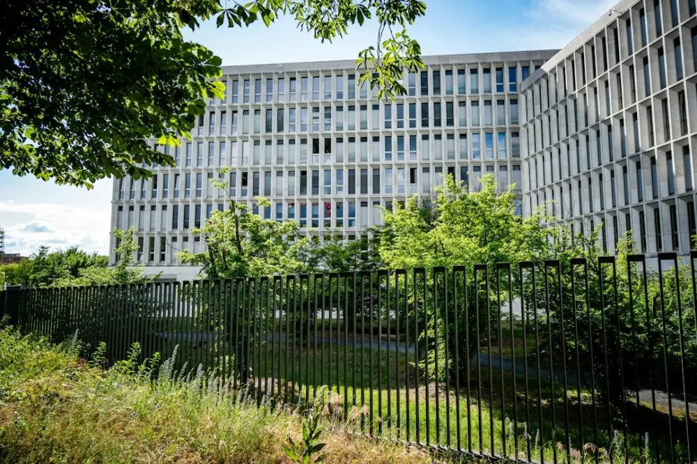 Large modern building with many windows behind a dark fence, illustrating evaluating public-policy implementation structures